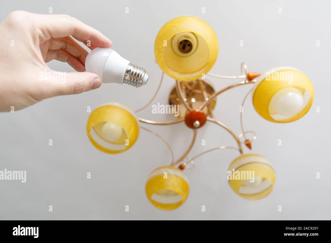 Hand Of Man Screwing New Lightbulb Into Ceiling Lamp Stock