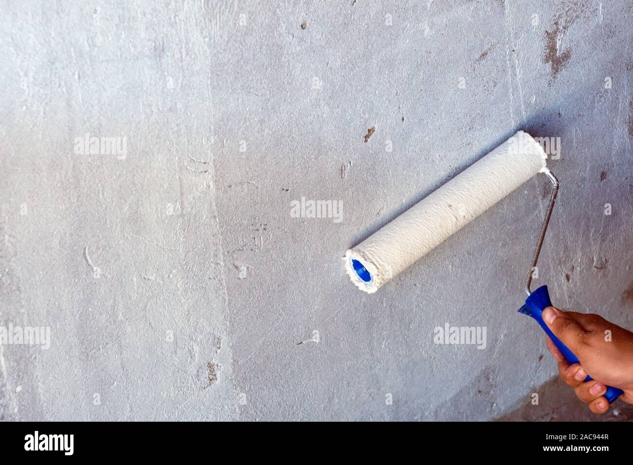 large roller to paint on the background texture of gray concrete wall Stock Photo