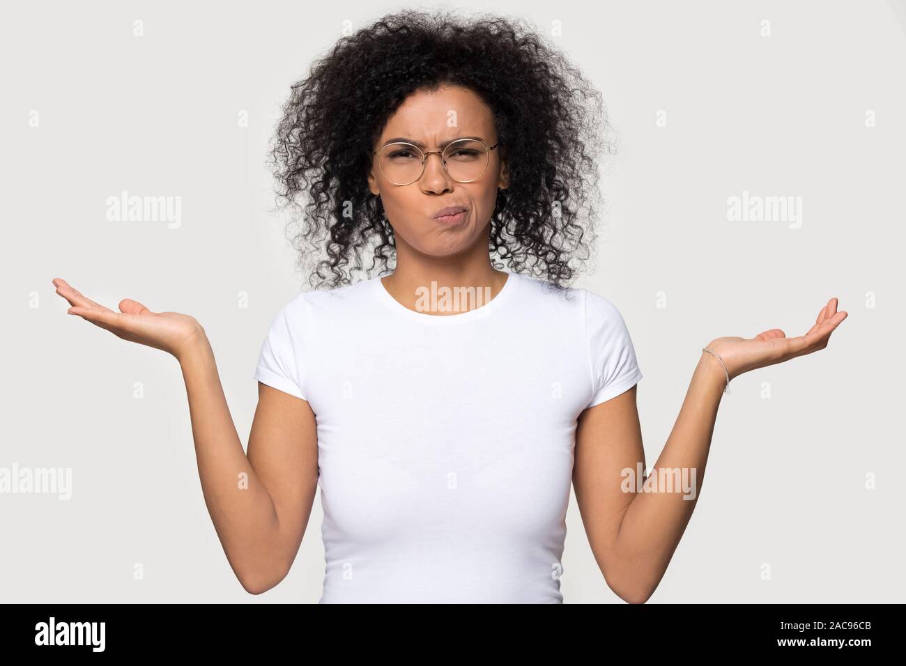 Doubtful African American woman shrugging shoulders, feeling confused Stock Photo