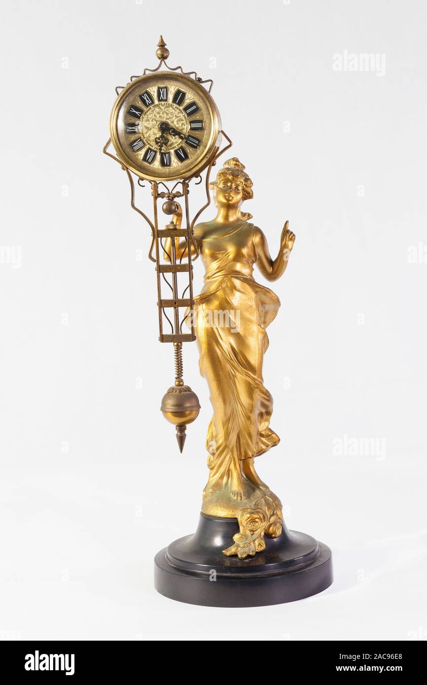 Gilt metal antique Art Nouveau pendulum clock of a lady in a  flowing dress holding the pendulum mechanism  with an ornate round dial in her hand over Stock Photo