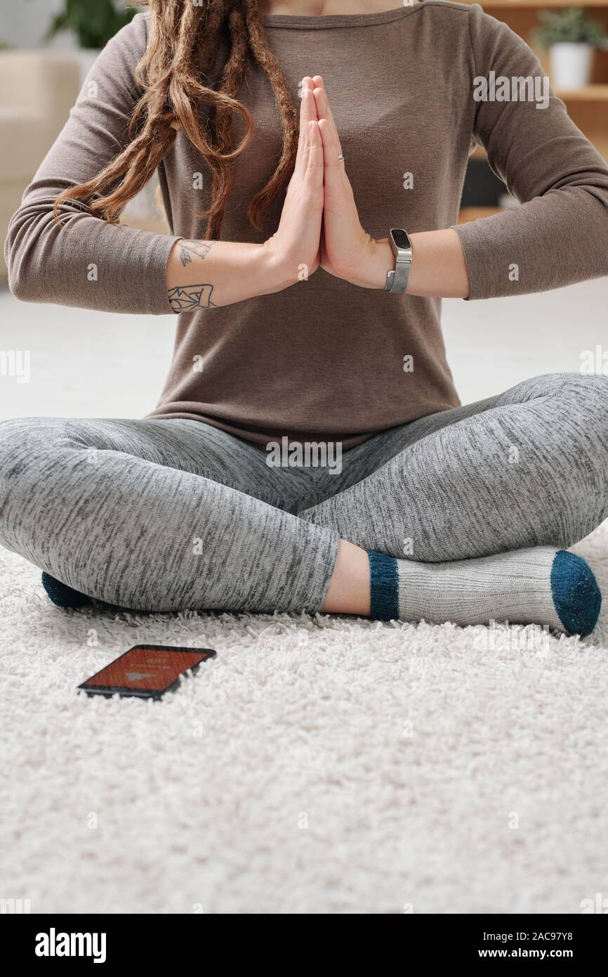 Active female sitting on the floor with crossed legs during yoga exercise Stock Photo