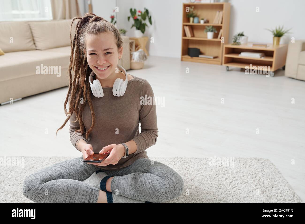 Cheerful young active woman with headphones using smartphone Stock Photo