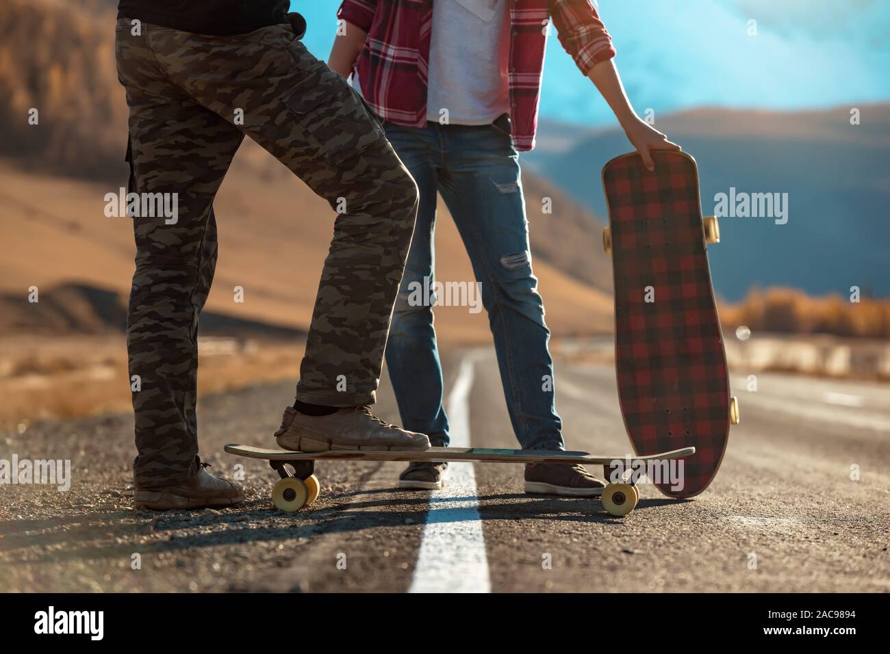 Two young longboarders stands with longboards on straight mountains road Stock Photo