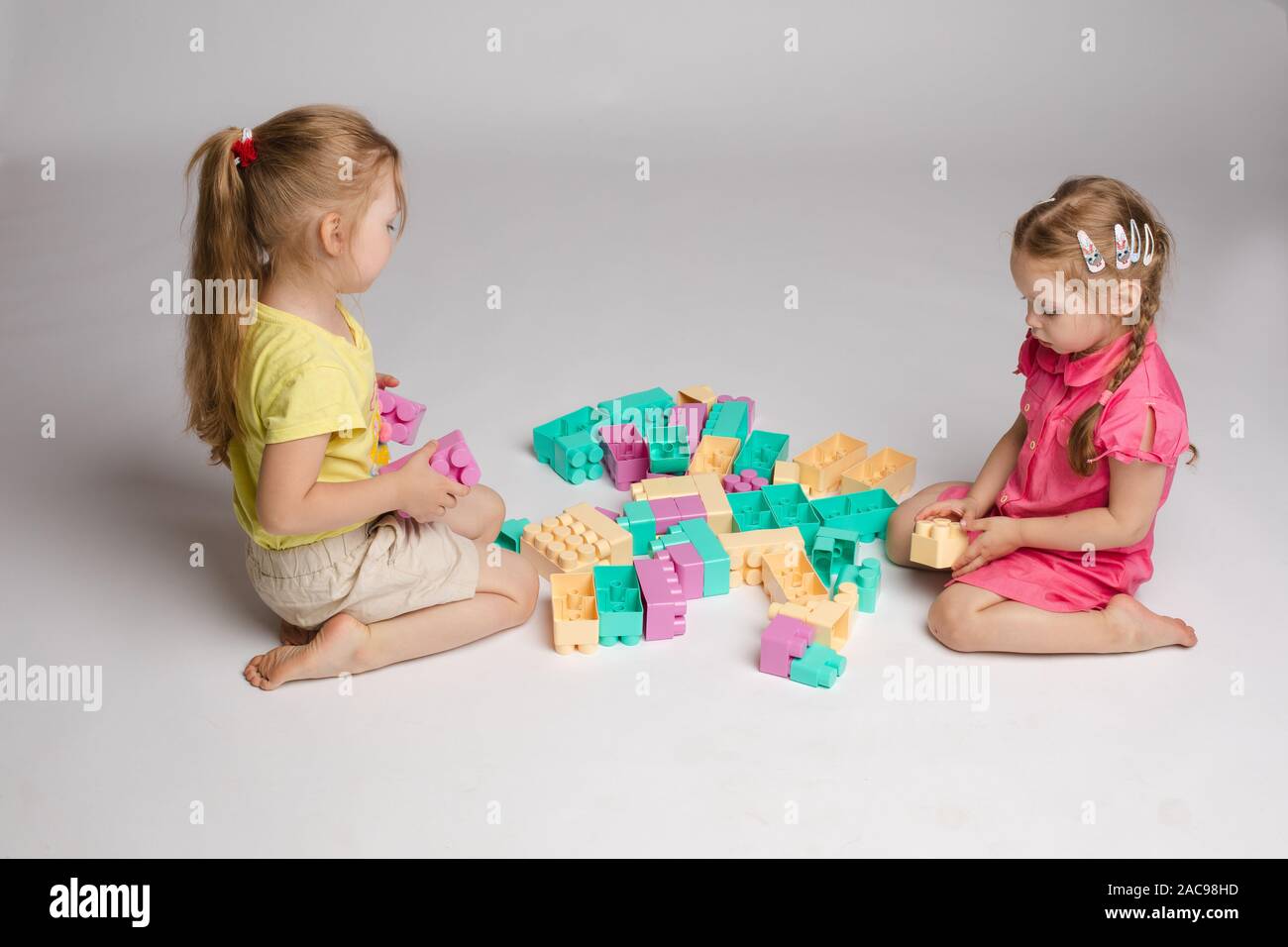 Two girls sitting on floor and playing with building blocks Stock Photo ...