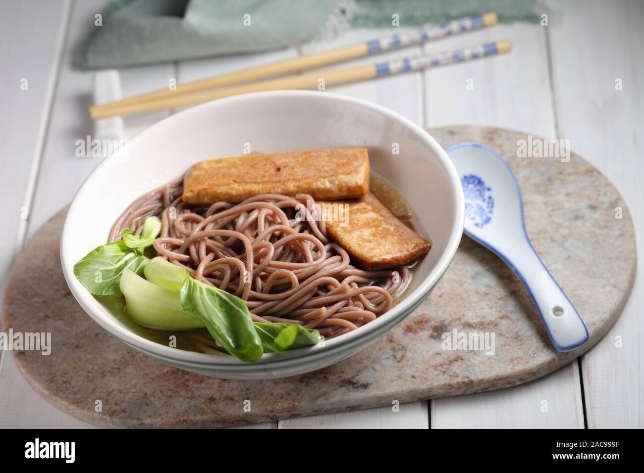 Portion of Soba noodle soup with slices of fried tofu and leafs of bok choy Stock Photo
