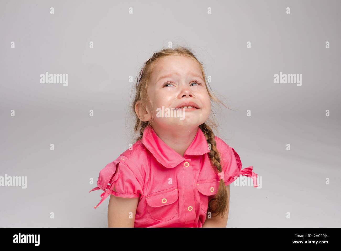 Adorable kid crying on the floor.he is looking at the camera while sobbing. Stock Photo