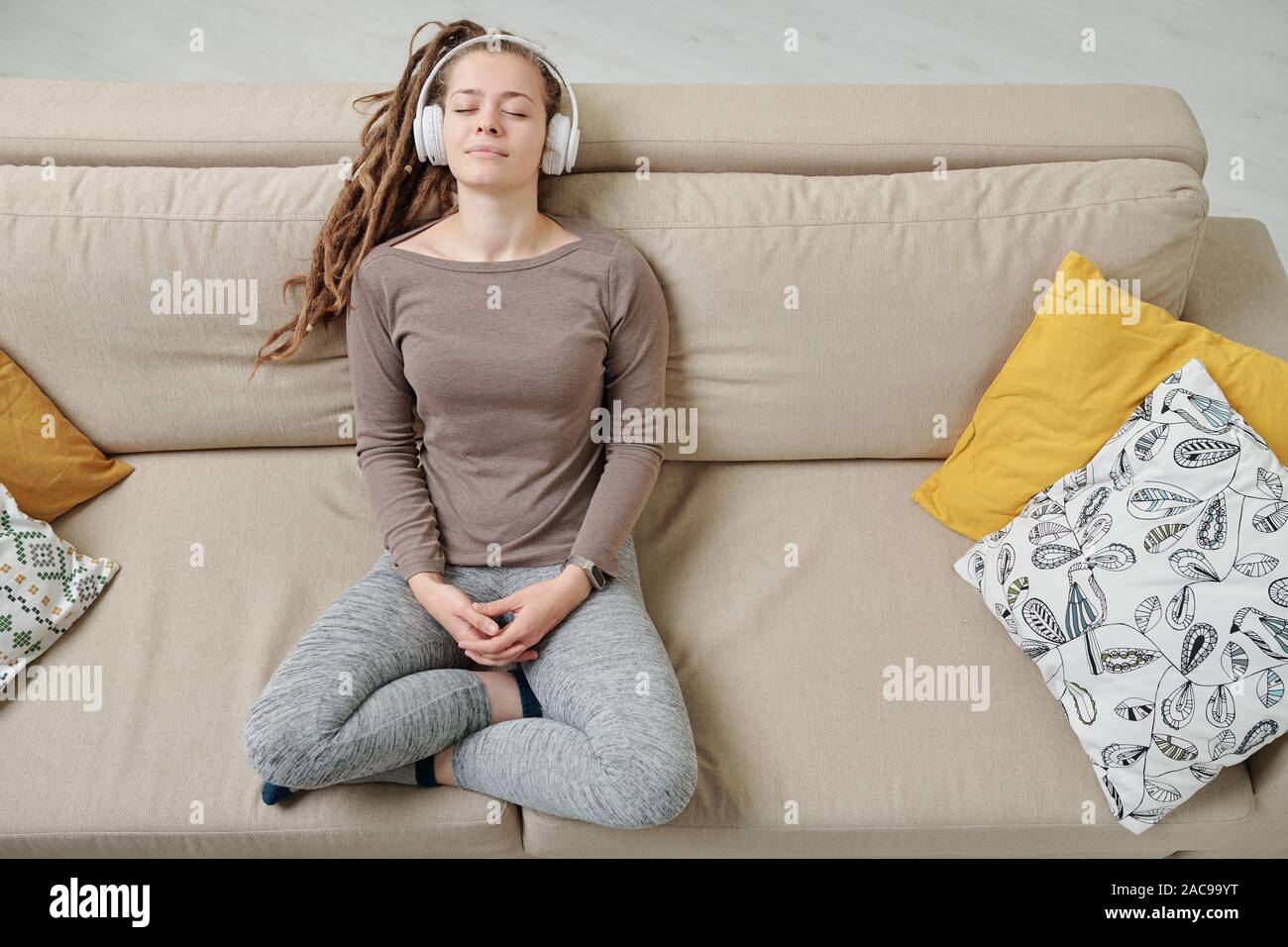 Peaceful girl relaxing on couch while listening to meditation music Stock Photo