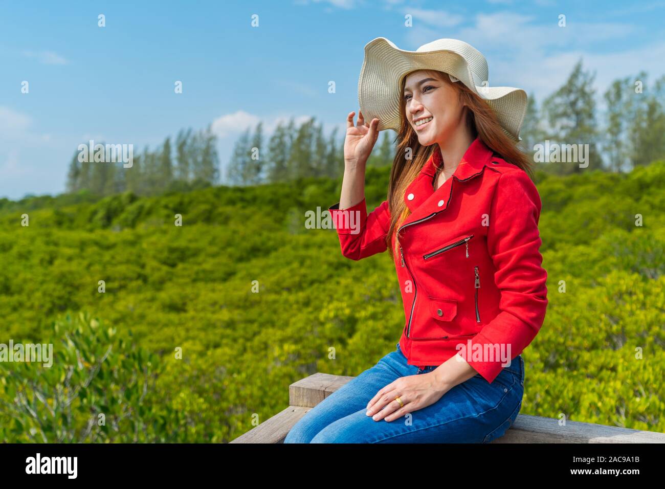 woman wearing red clothes in wooden bridge at Tung Prong Thong or Golden Mangrove Field, Rayong province, Thailand Stock Photo