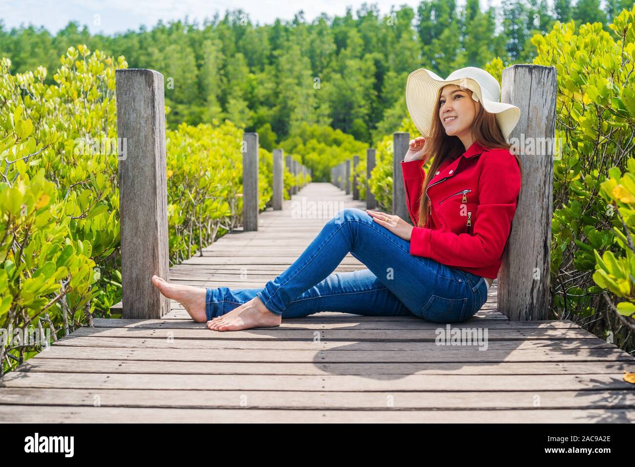 woman wearing red clothes in wooden bridge at Tung Prong Thong or Golden Mangrove Field, Rayong province, Thailand Stock Photo