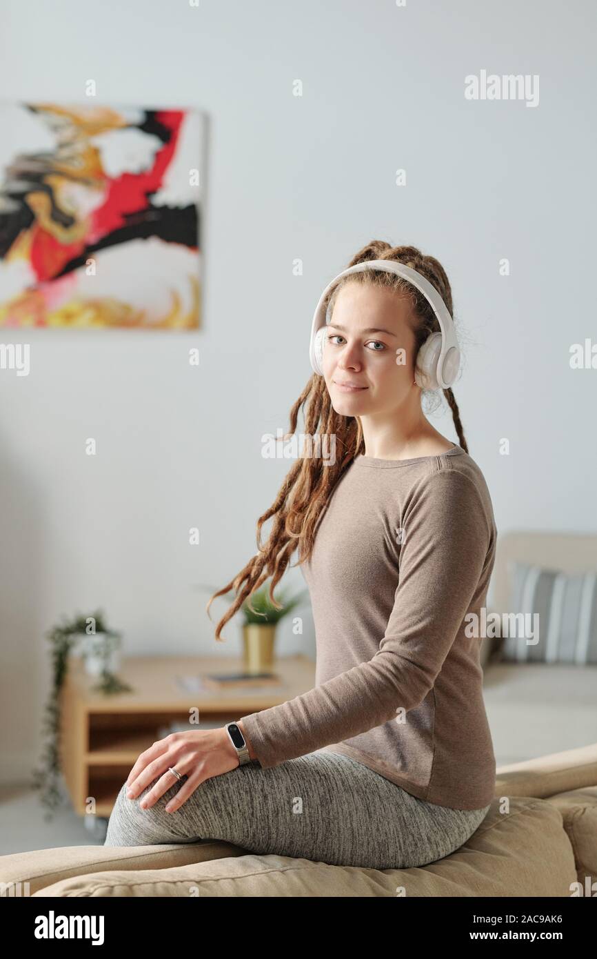 Pretty Girl With Dreadlocks Sitting On Soft Sofa While