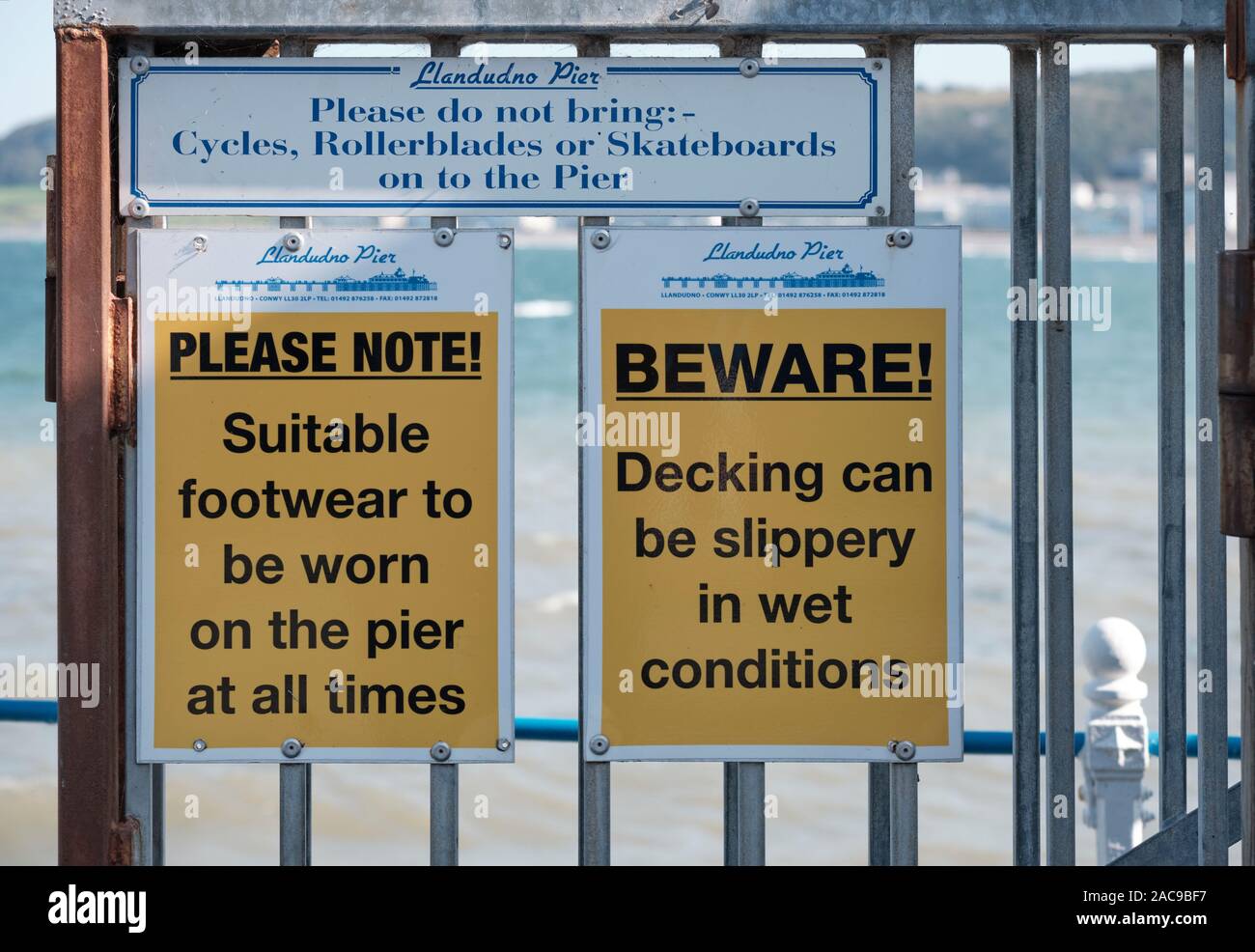 Warning signs on Llandudno Pier: Beware slippery, Footwear worn, No cycles...  Llandudno, Wales, Stock Photo