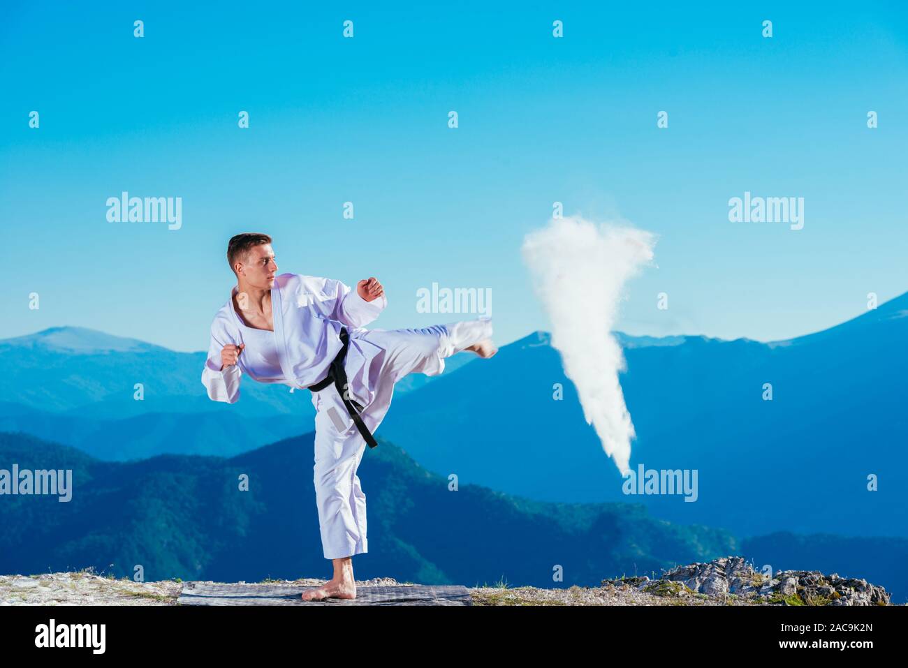 Fit karate athlete kicking a cup filled whit fluor causing a big splash ...