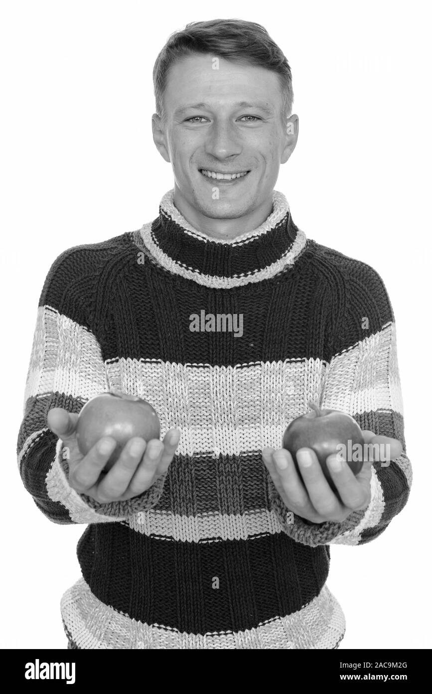 Studio shot of young happy Caucasian man holding green and red apple ...