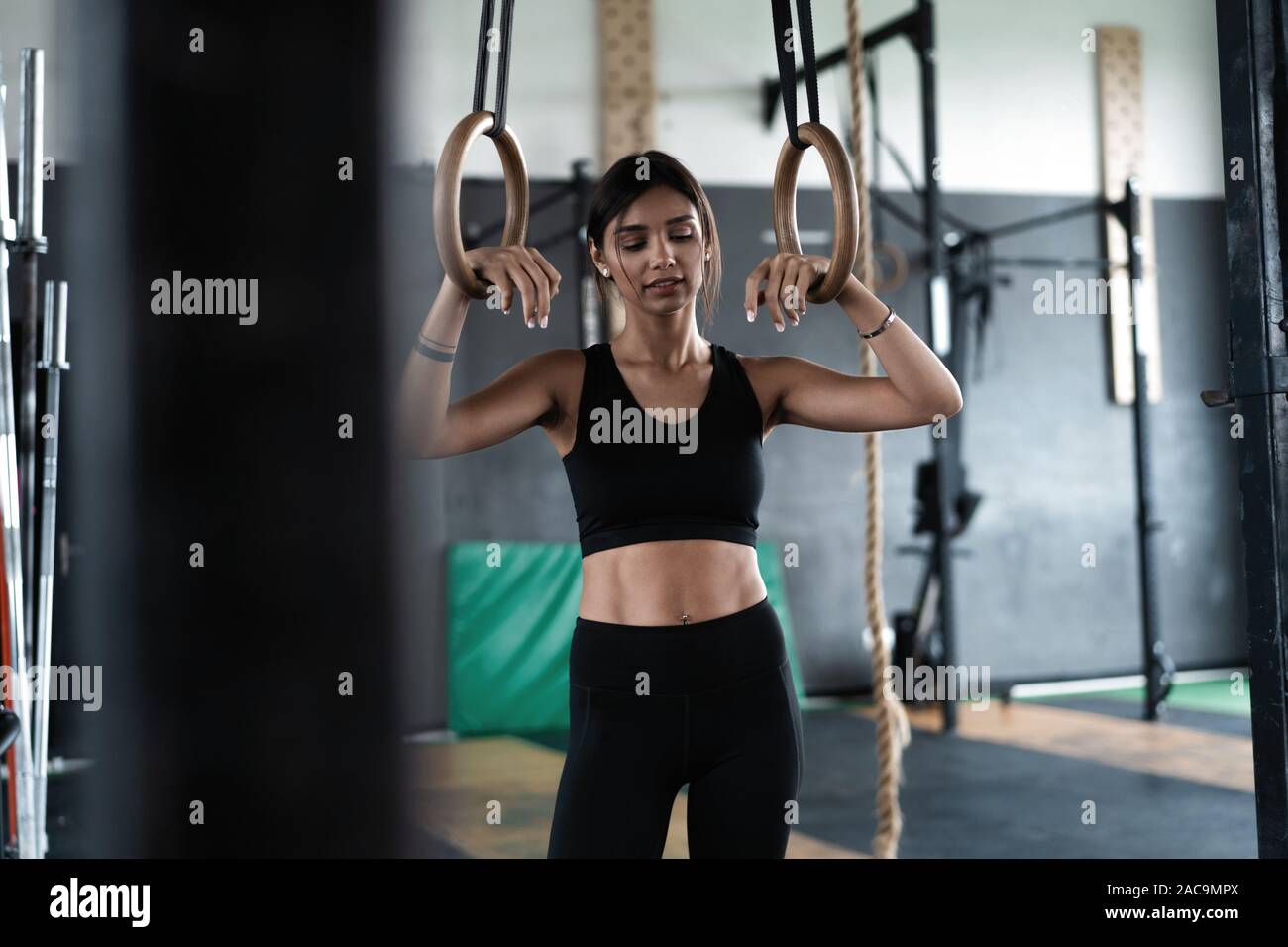 Exercising woman holding gymnast rings. Female taking rest after intense  dip ring workout at gym Stock Photo - Alamy