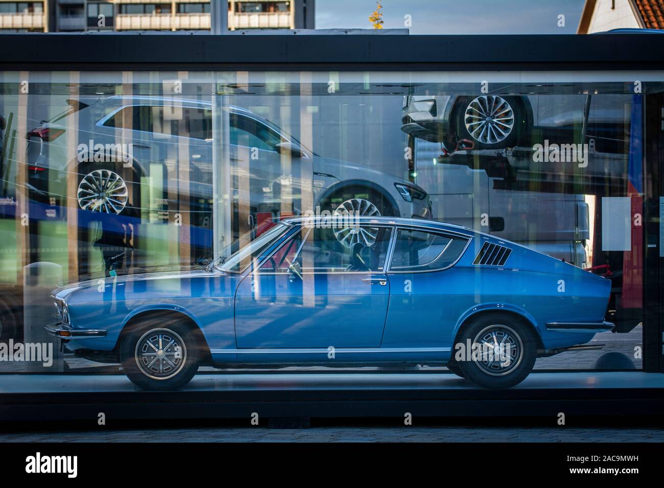 A 1972 Audi 100 Coupes Stands Outside The Audi Museum With A Transporter Carrying New Audi S Behind Stock Photo Alamy