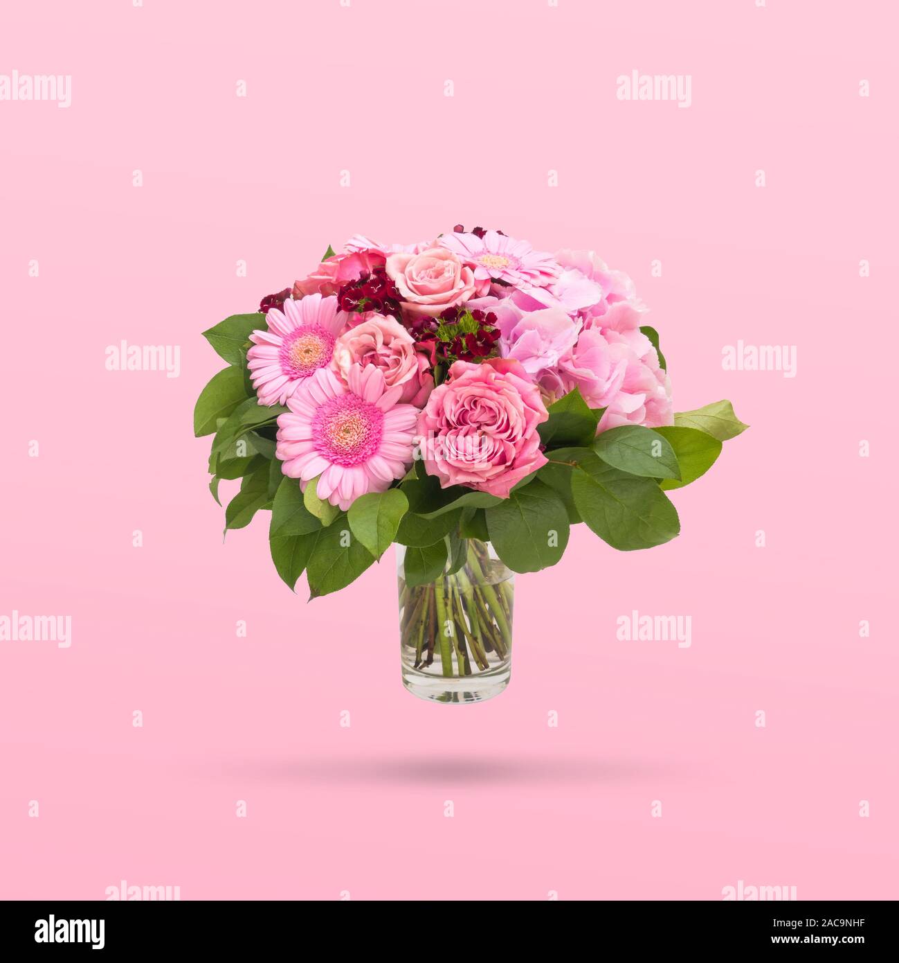 Beautiful bouquet flowers in glass vase floating on pink background, minimal design Stock Photo