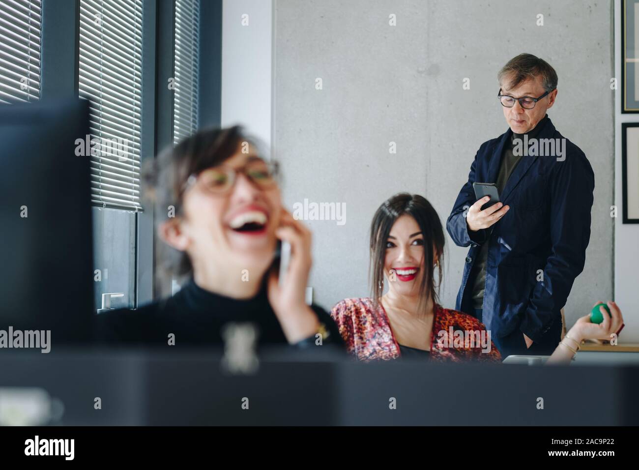 Portrait of happy businesswoman using the anti stress ball in creative office. Coworkers talking on the phone. Happy and busy office life concept. Stock Photo