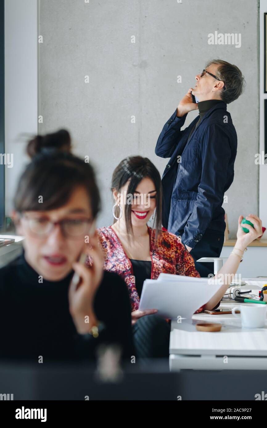 Portrait of happy businesswoman using the anti stress ball in creative office. Coworkers talking on the phone. Happy and busy office life concept. Stock Photo