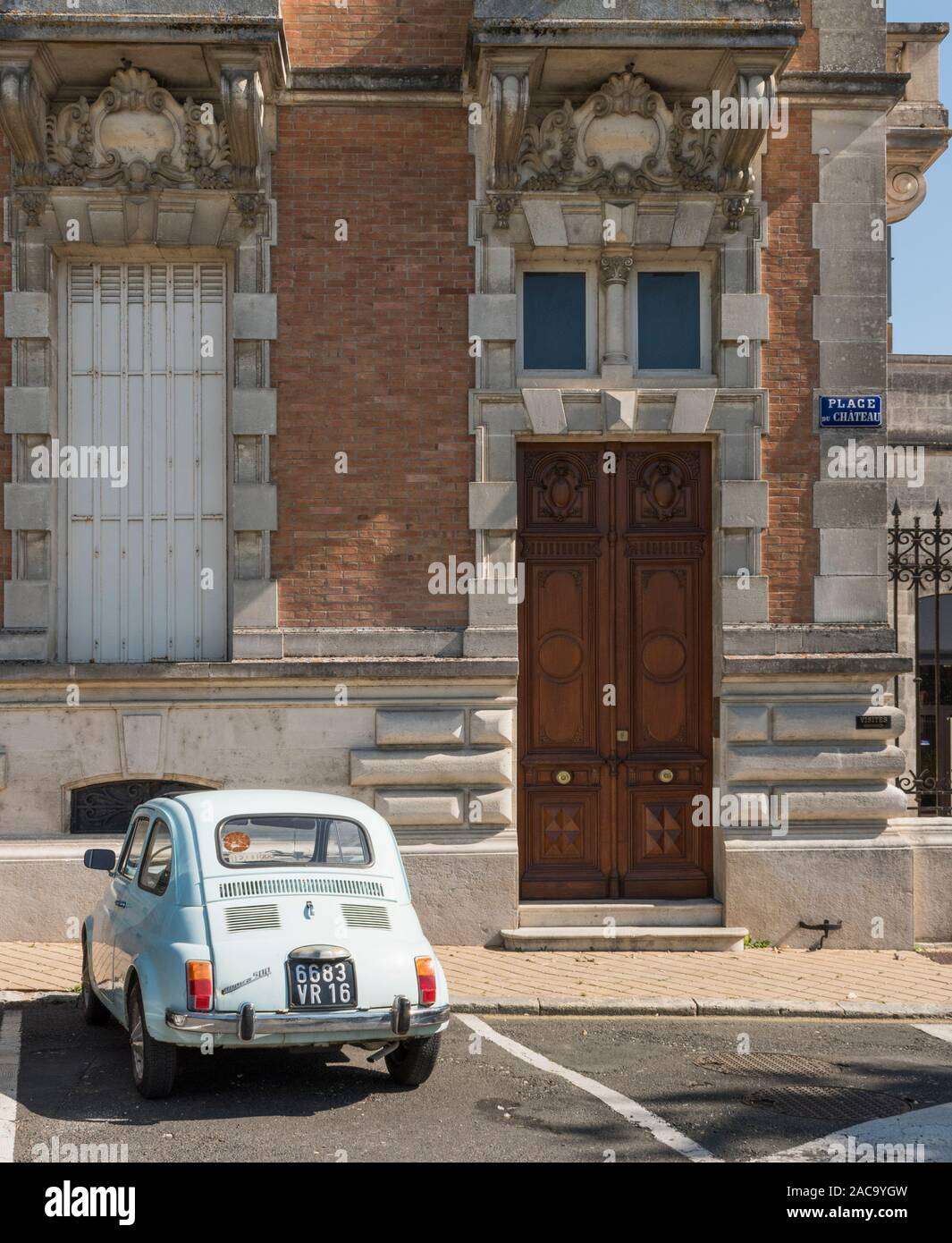 Fiat 500 parked outside the grand building in Jarnac, Charente, France Stock Photo
