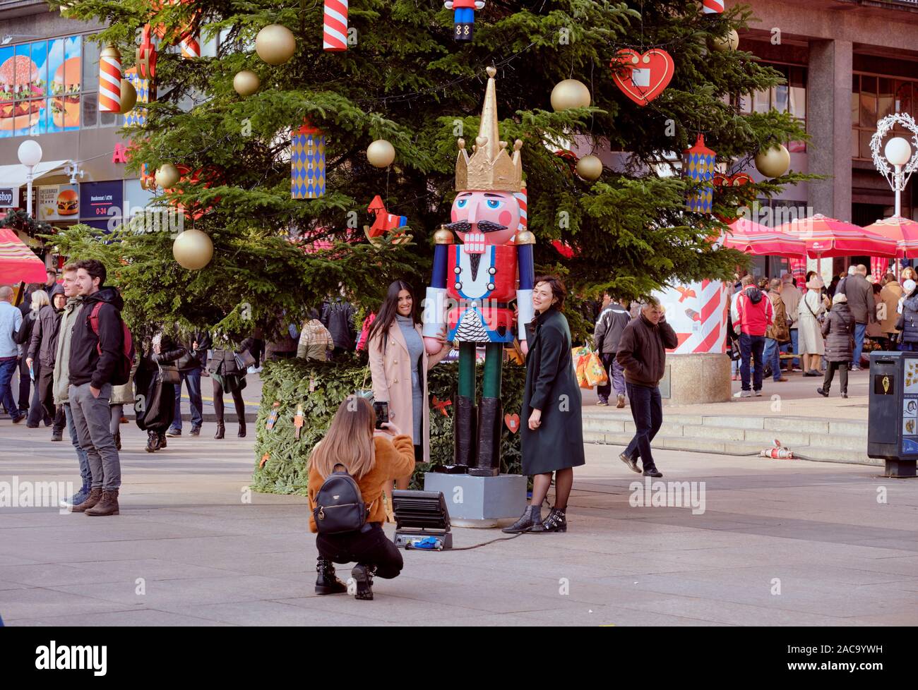 Two lovely ladies posing next to one of the Nutcracker statue next to large Christmas tree in centre square at Advent Market. Zagreb, Croatia Stock Photo