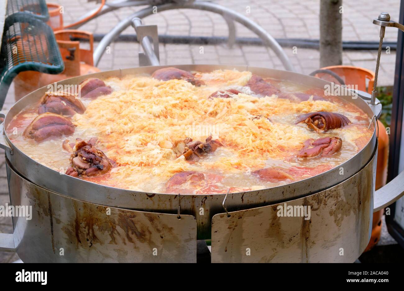 Focus on traditional Croatian Buncek- Pork Hock preparation in large stewing pot with cabbage. View of the meat in boiling broth. Advent Market Zagreb Stock Photo