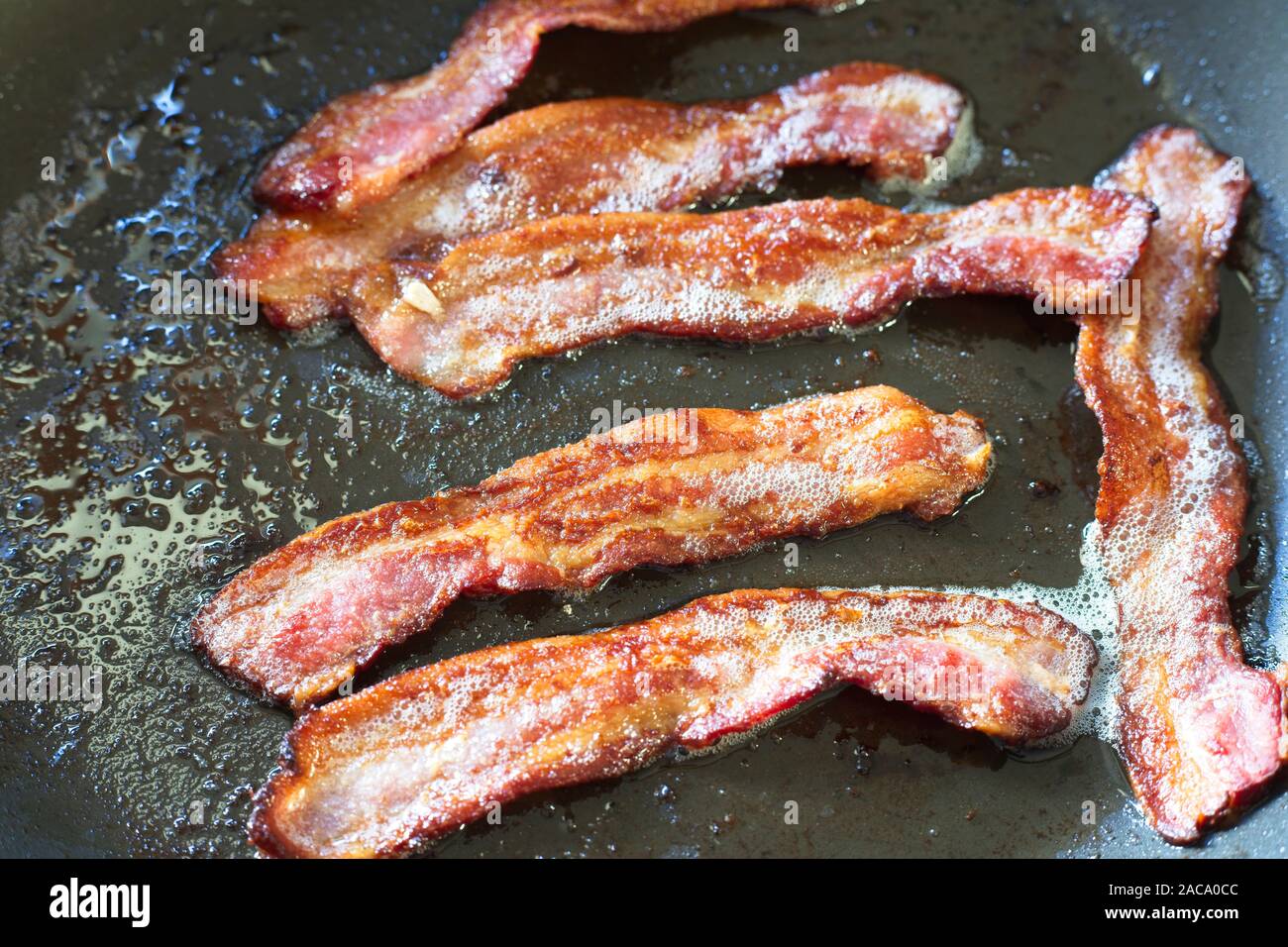 Streaky bacon being fried in a frying pan, UK Stock Photo