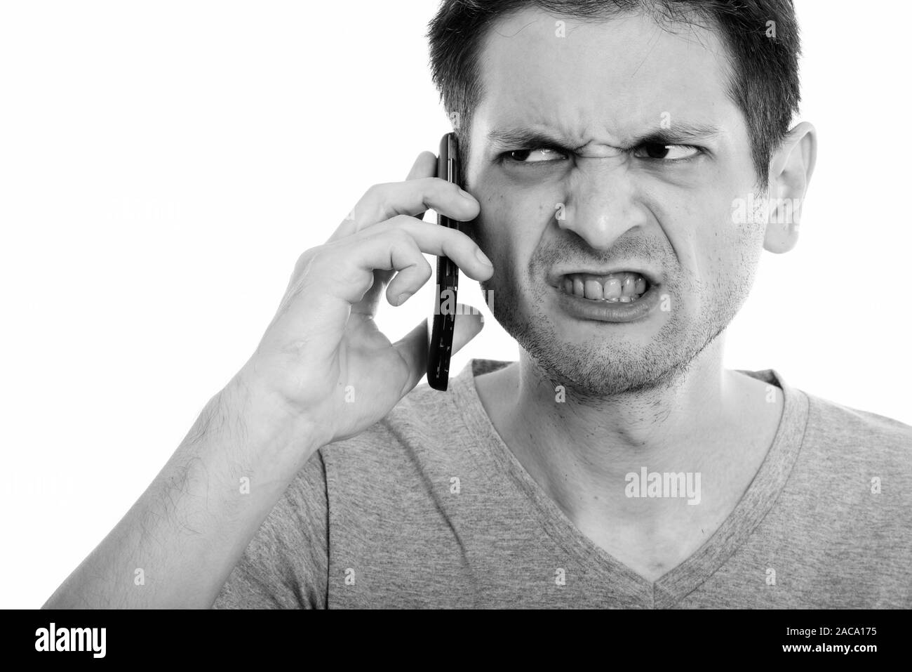 Close up of angry young man talking on mobile phone Stock Photo