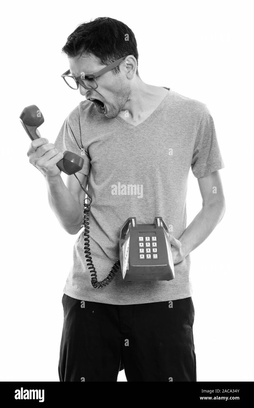 Studio shot of angry young man shouting at old telephone Stock Photo