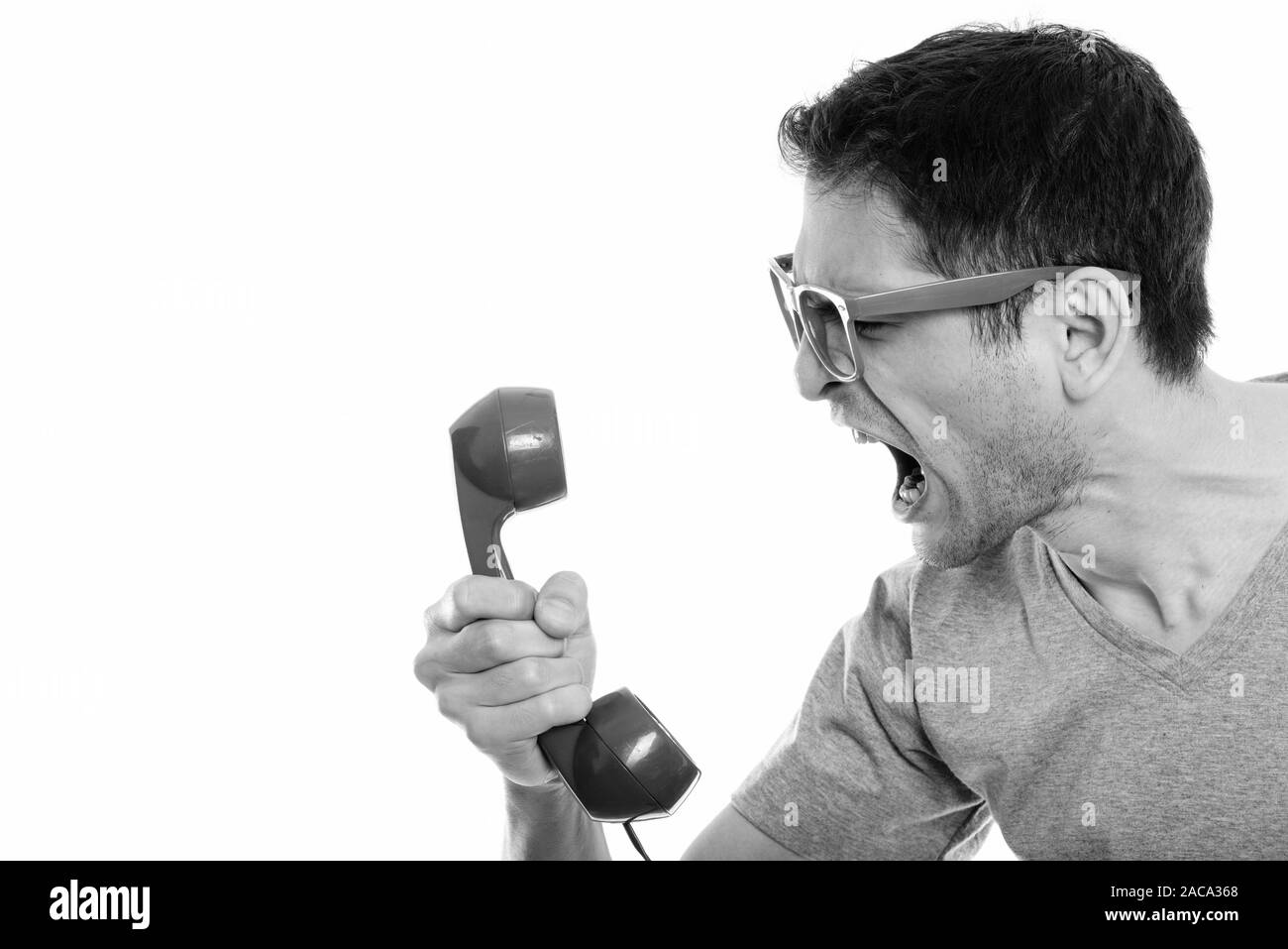 Close up of angry young man shouting at old telephone Stock Photo