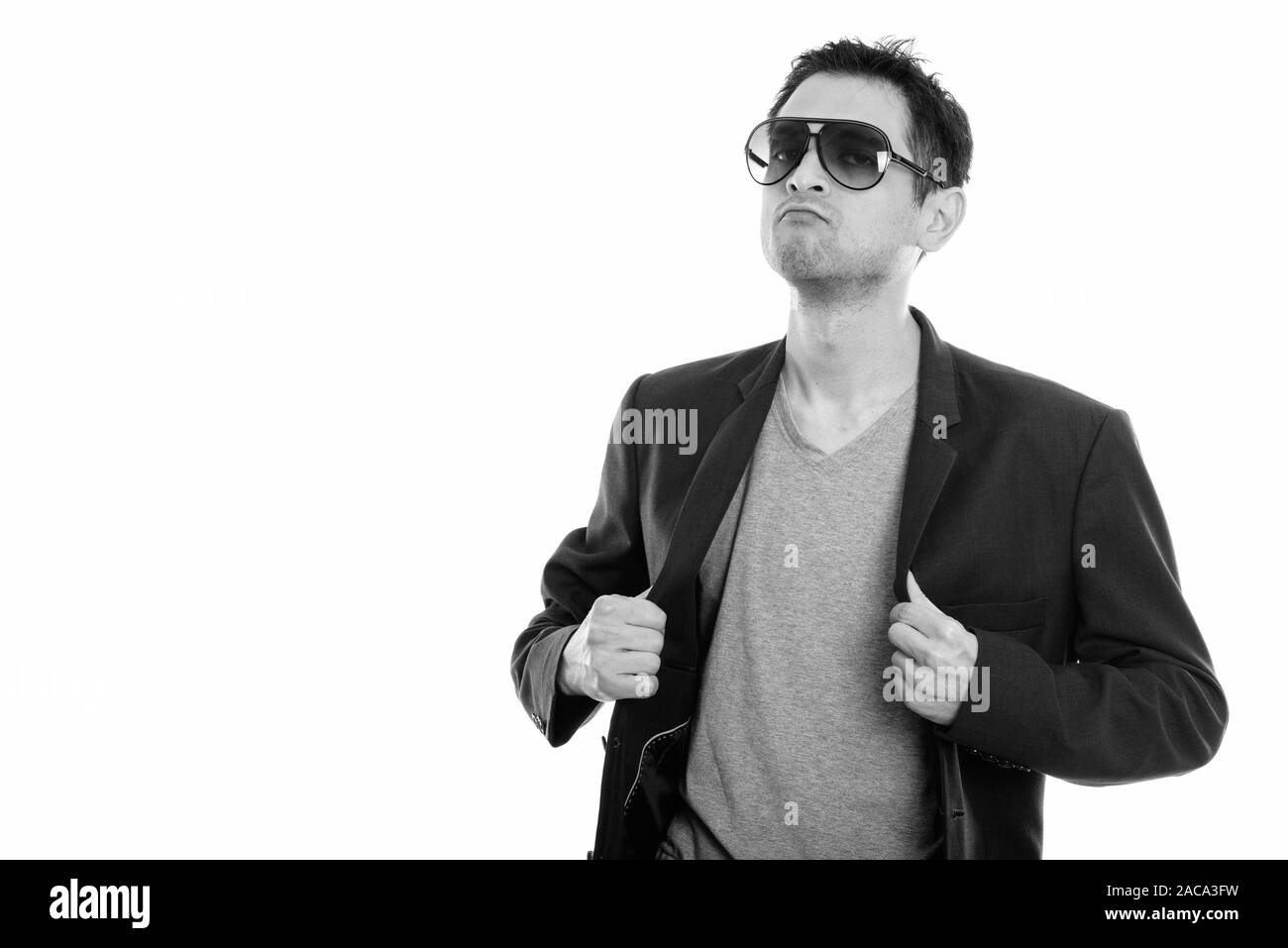Studio shot of cool young man wearing sunglasses while fixing his jacket Stock Photo