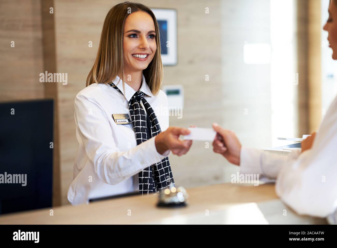 Receptionist Giving Key Card To Businesswoman At Hotel Front Desk