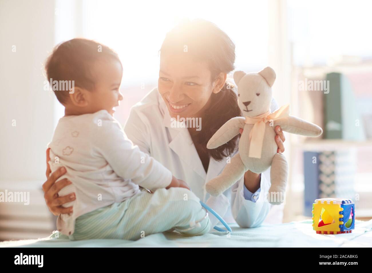 Young female doctor smiling and playing with baby boy during her visit Stock Photo