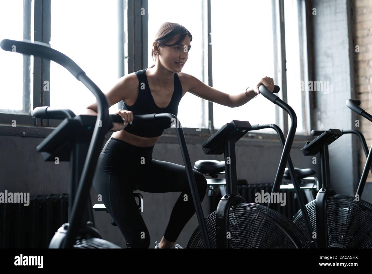 Fit young woman using exercise bike at the gym. Fitness female using