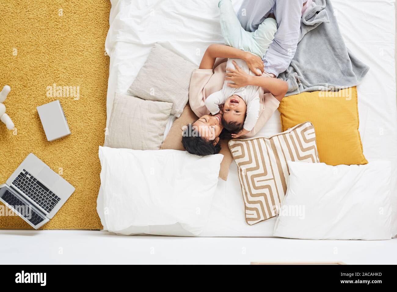 High angle view of happy young mother lying and embracing her child in the bed in the bedroom at home Stock Photo