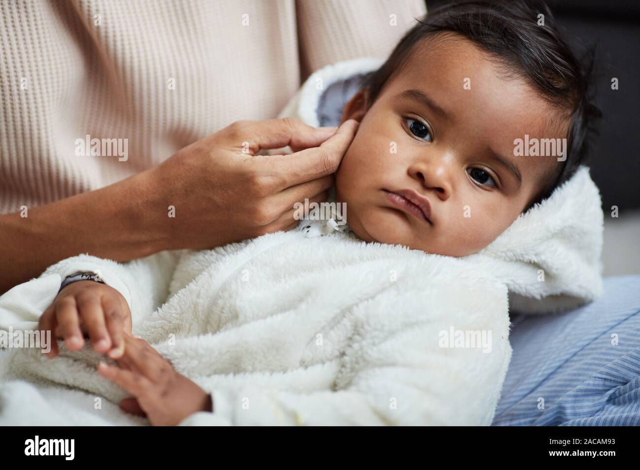 Close-up of cute baby boy lying on his mother's hands while she stroking his head and cradling him Stock Photo