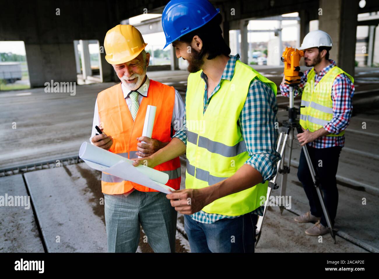 Two satisfied engineers talking at building site with construction structure in background Stock Photo