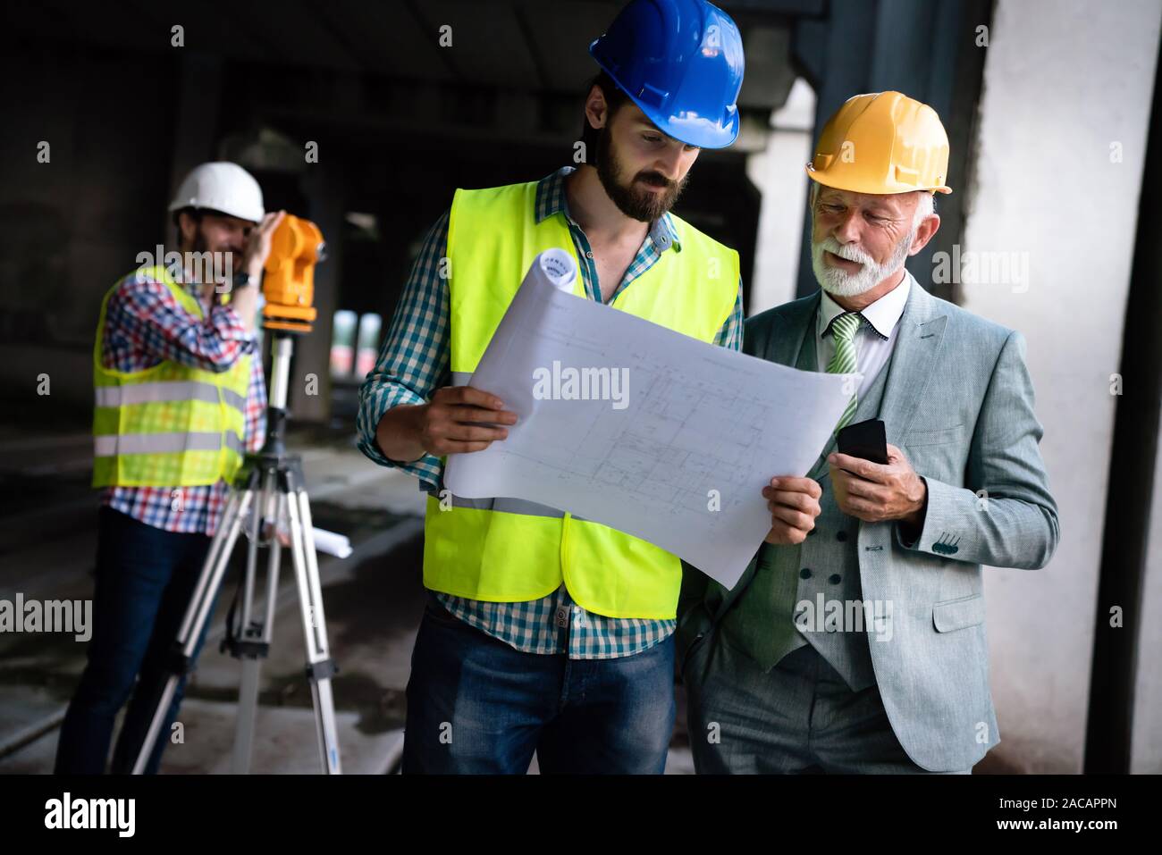 Male architects analyzing blueprint at construction site Stock Photo