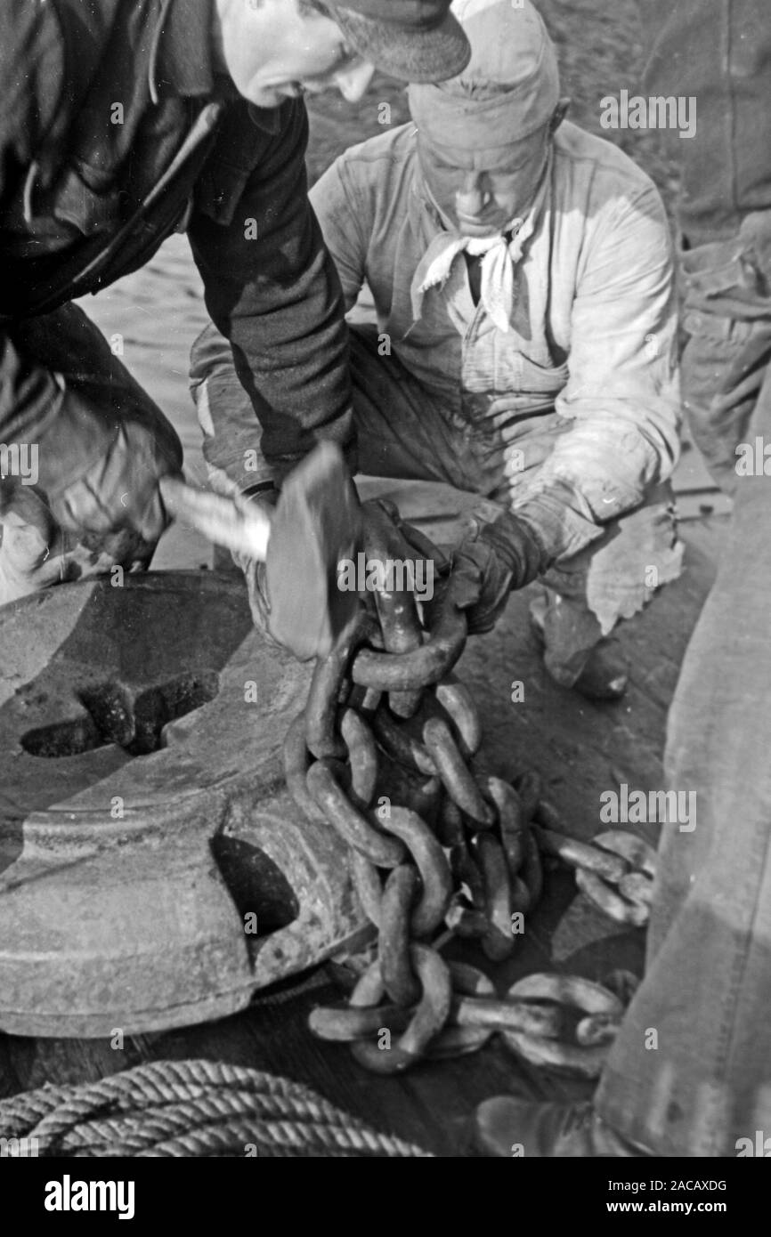 Schiffsarbeiter befestigen schmiedeeiserne Sperrkette, Emden, Niedersachsen, Deutschland, 1950. Ship workers fasten wrought iron barrier chain, Emden, Lower Saxony, Germany, 1950. Stock Photo