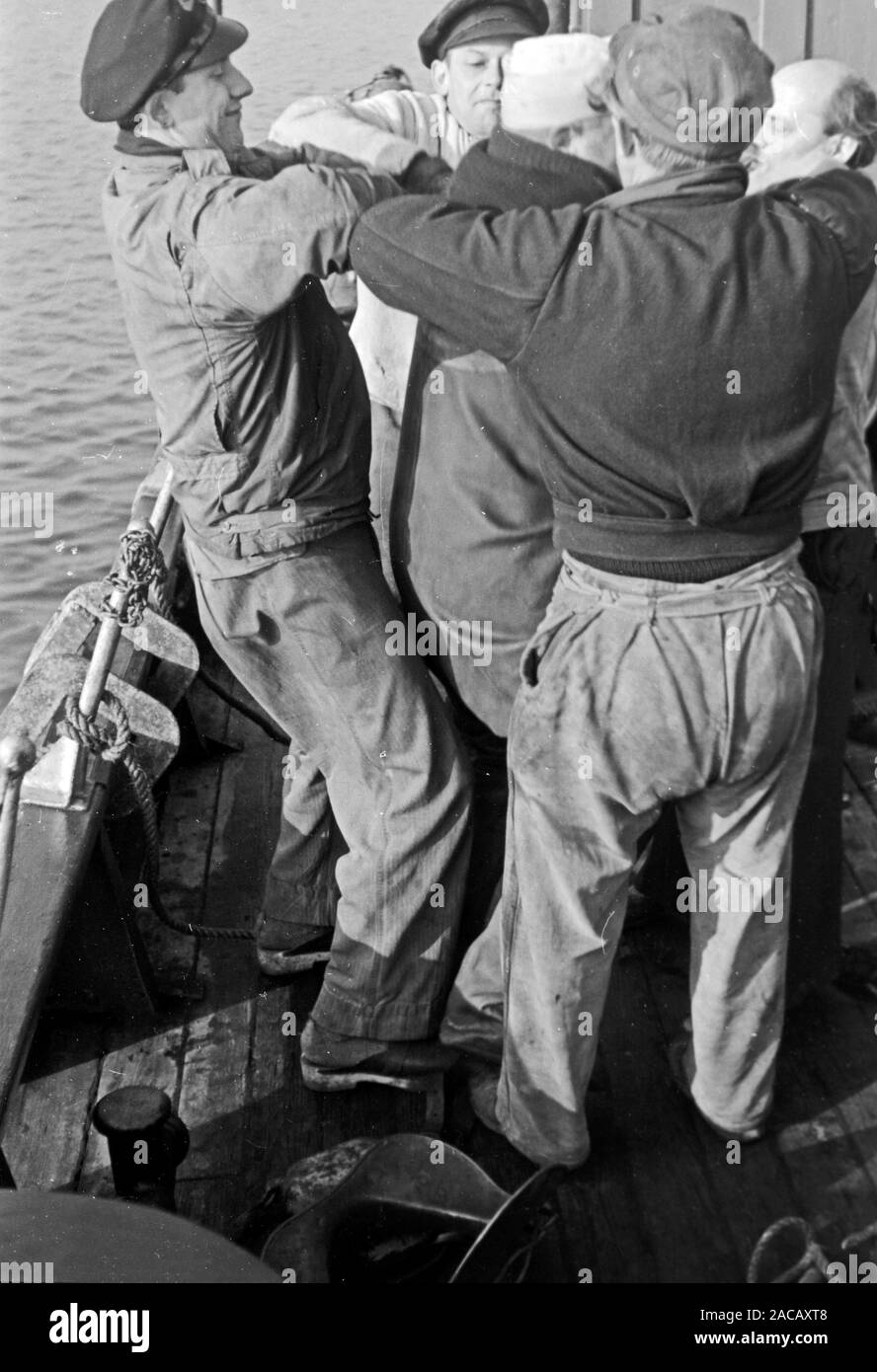 Schiffsarbeiter helfen Bojen Taucher in Taucheranzug, Emden, Niedersachsen, Deutschland, 1950. Ship workers help buoys divers in diving suit, Emden, Lower Saxony, Germany, 1950s. Stock Photo