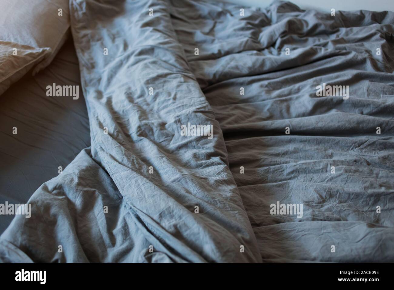 A gray cotton sheet and blankets with pillows on the bed Stock Photo