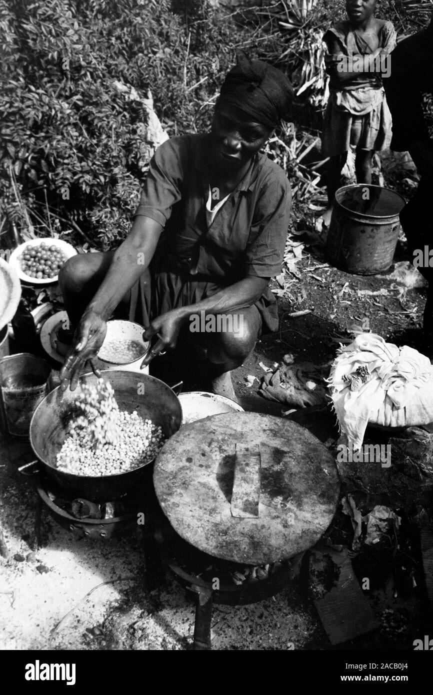 Zubereitun von Reis mit Bohnen auf Holzfeuer, 1967. Preparing rice and beans over log fire, 1967. Stock Photo