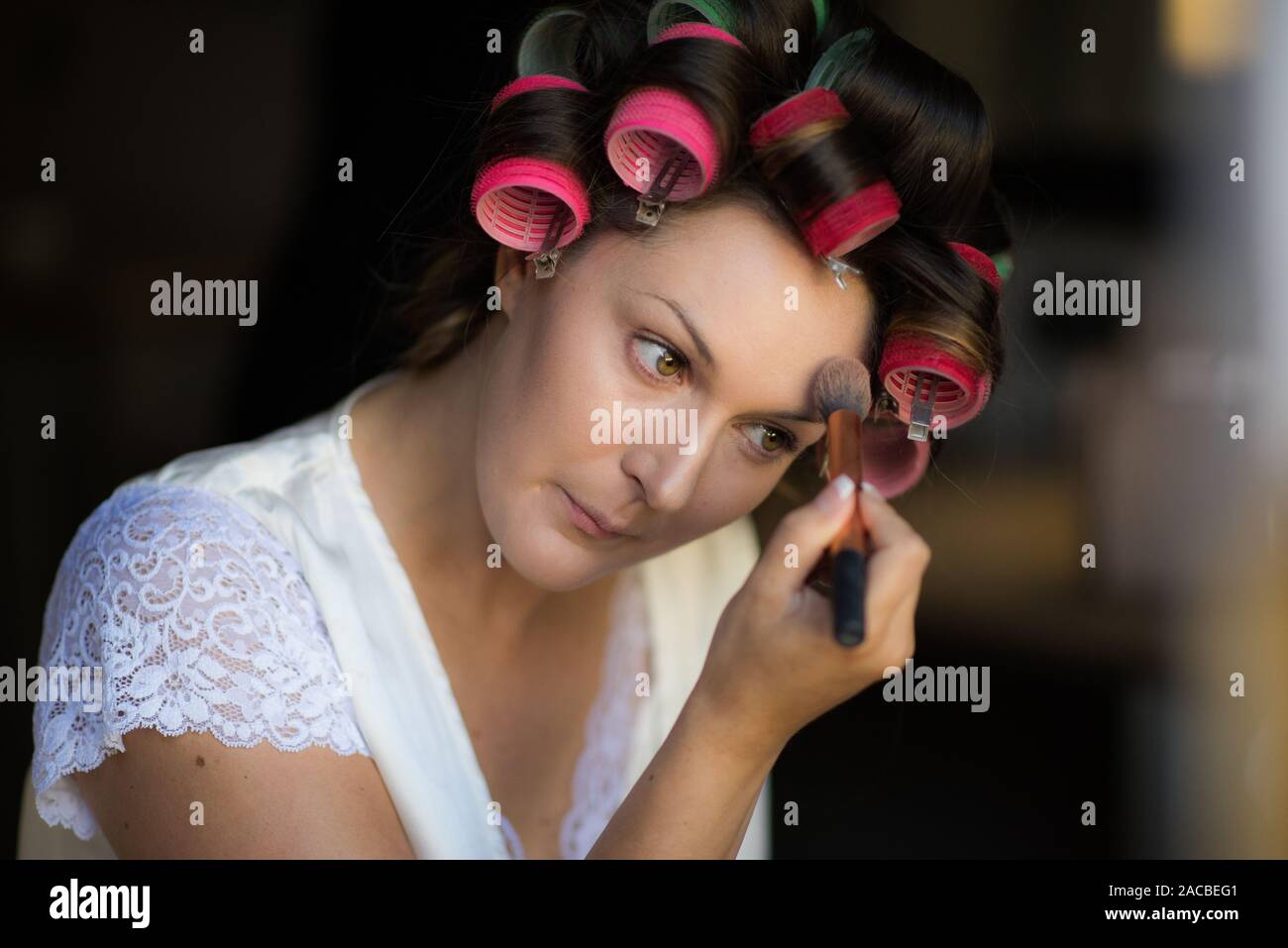 A beautiful bride to be getting ready during bridal preparation on the morning of her wedding day. Having her hair and makeup done, finishing touches Stock Photo