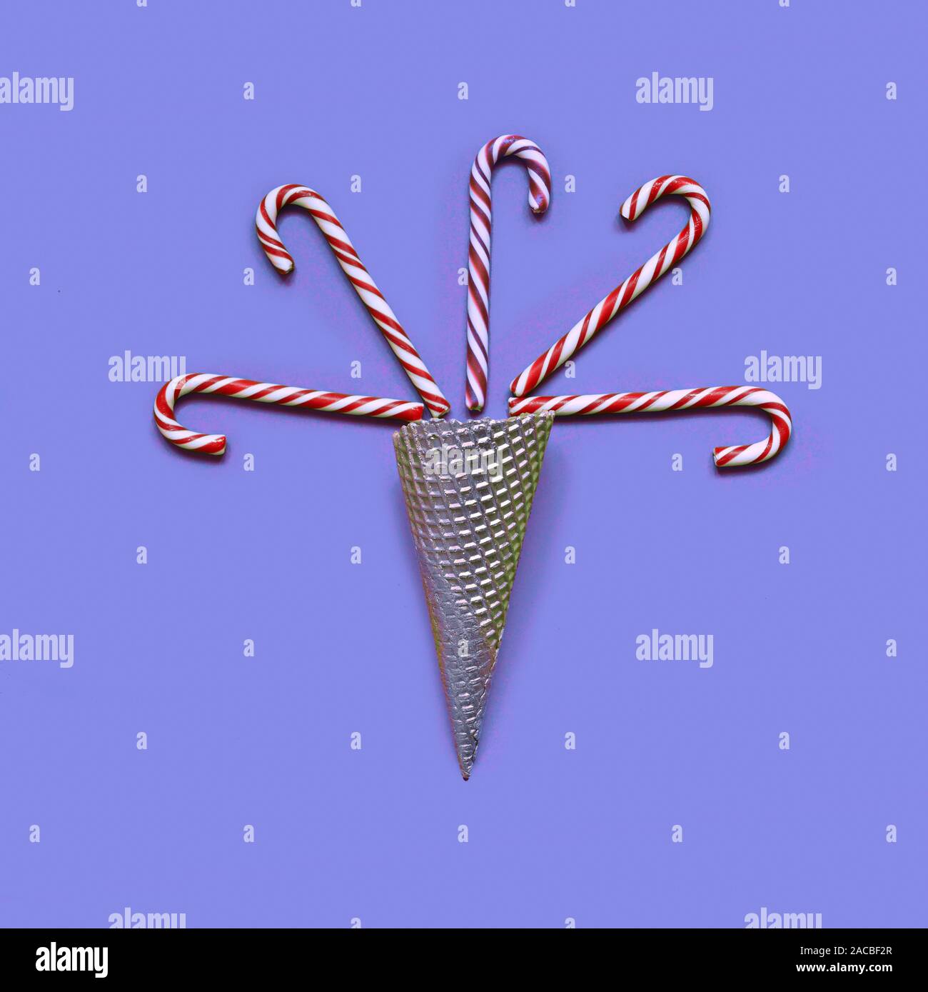 Christmas candy canes in Ice Cream Cone on purple background Stock Photo