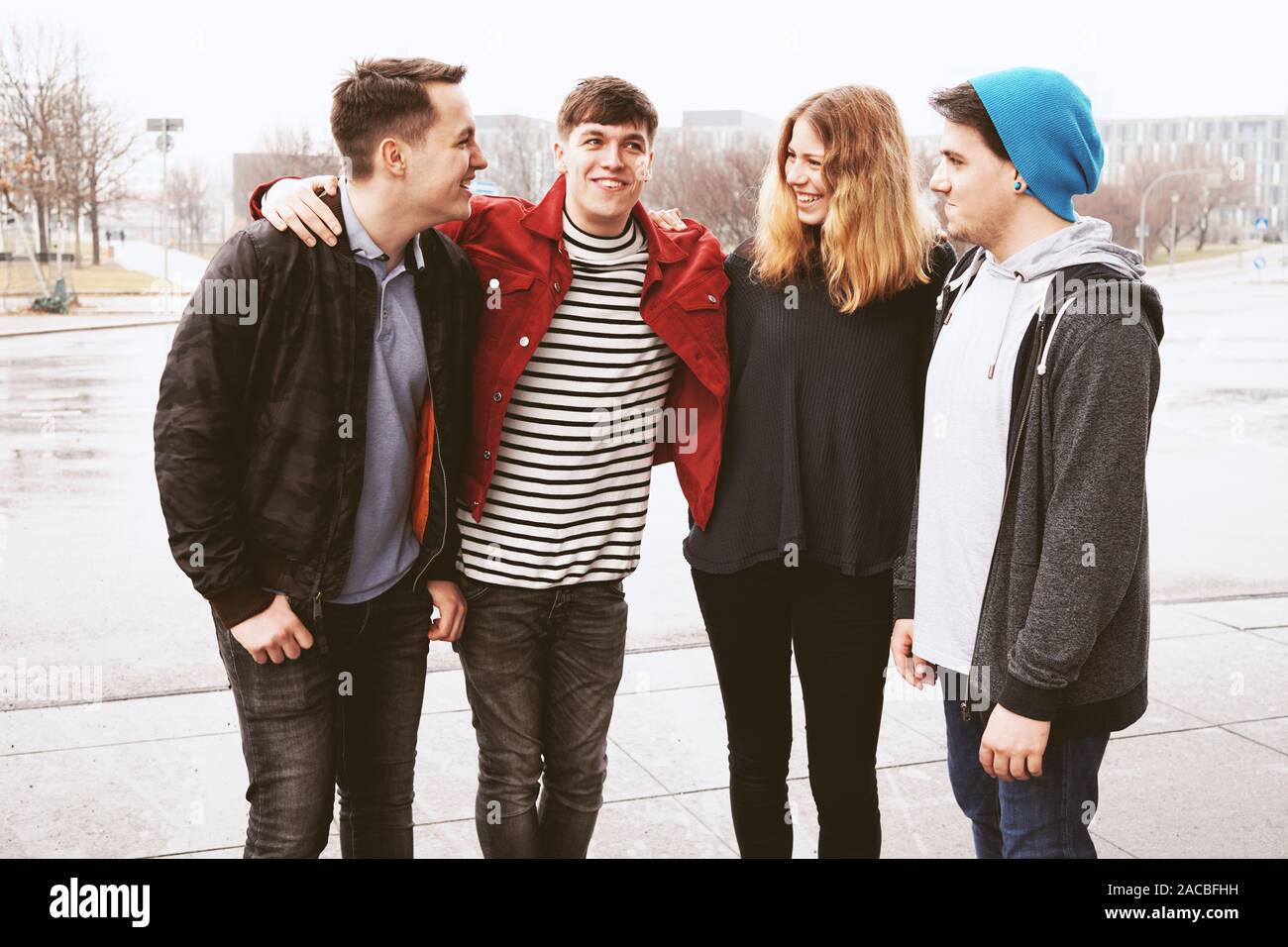 group of four young urban teenage friends having fun and laughing together despite bad weather - candid real people Stock Photo