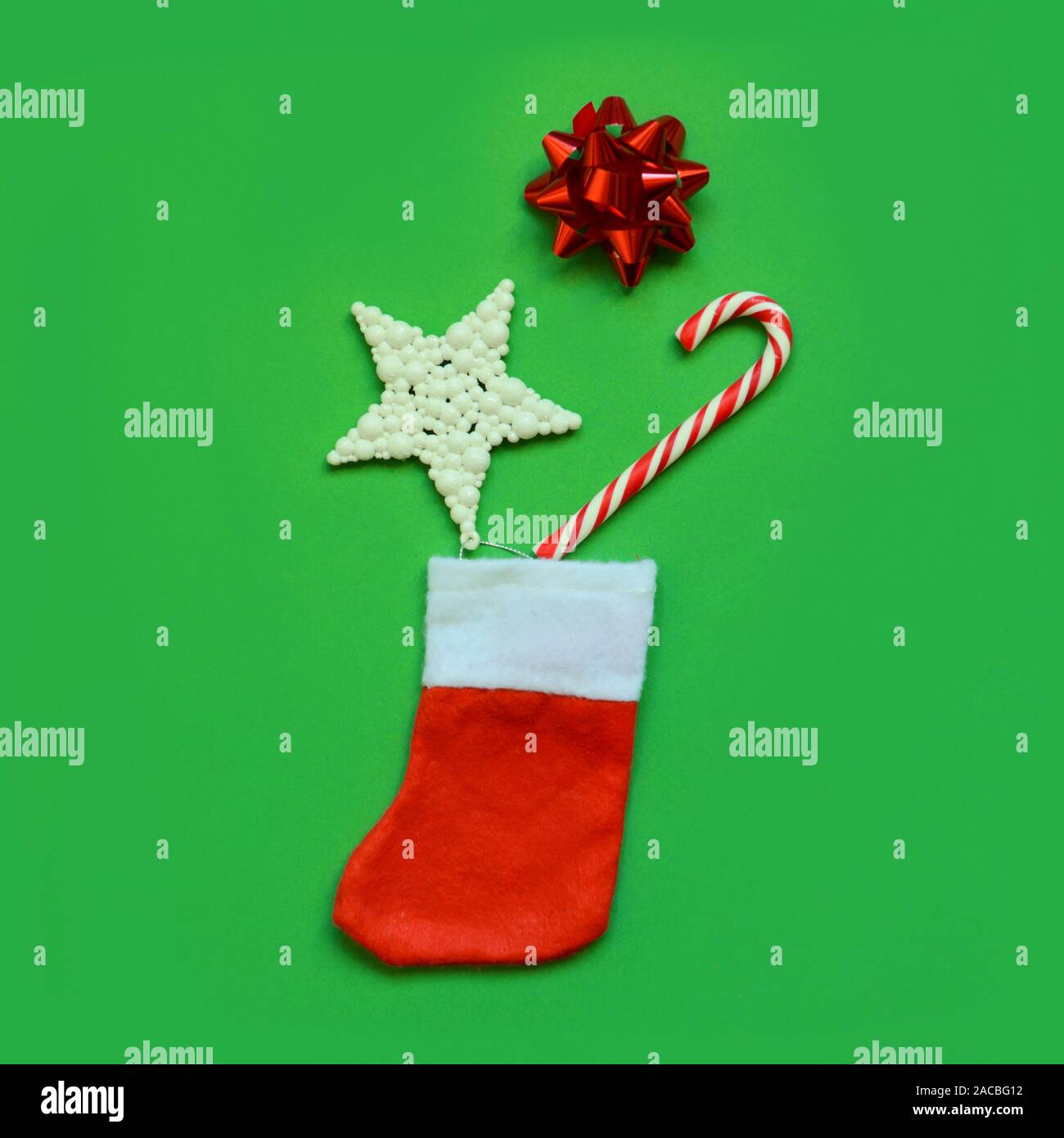 Christmas composition. Frame made of christmas sock, gifts, candy cane, star on green background. Flat lay, top view, copy space. Stock Photo