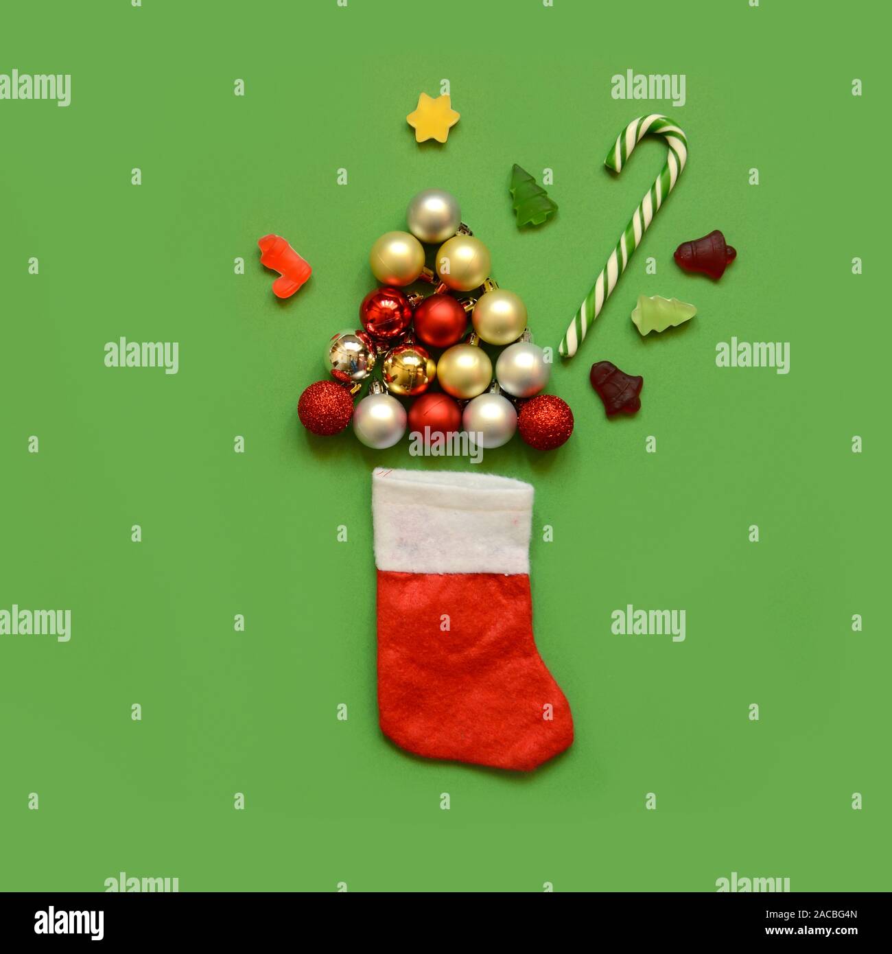 Christmas composition. Christmas sock with tree from balls,candy canes and sweets on green background. Christmas, winter, new year concept. Flat lay, Stock Photo