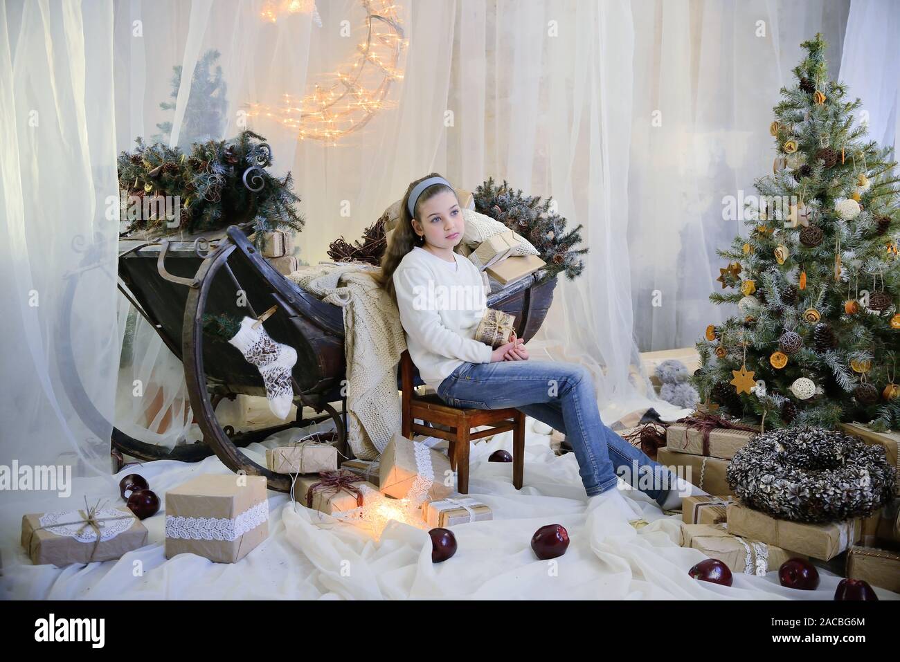 Merry Christmas and happy holidays! Cute dreamy girl sitting in interior of Christmas decorations pastel colors Stock Photo