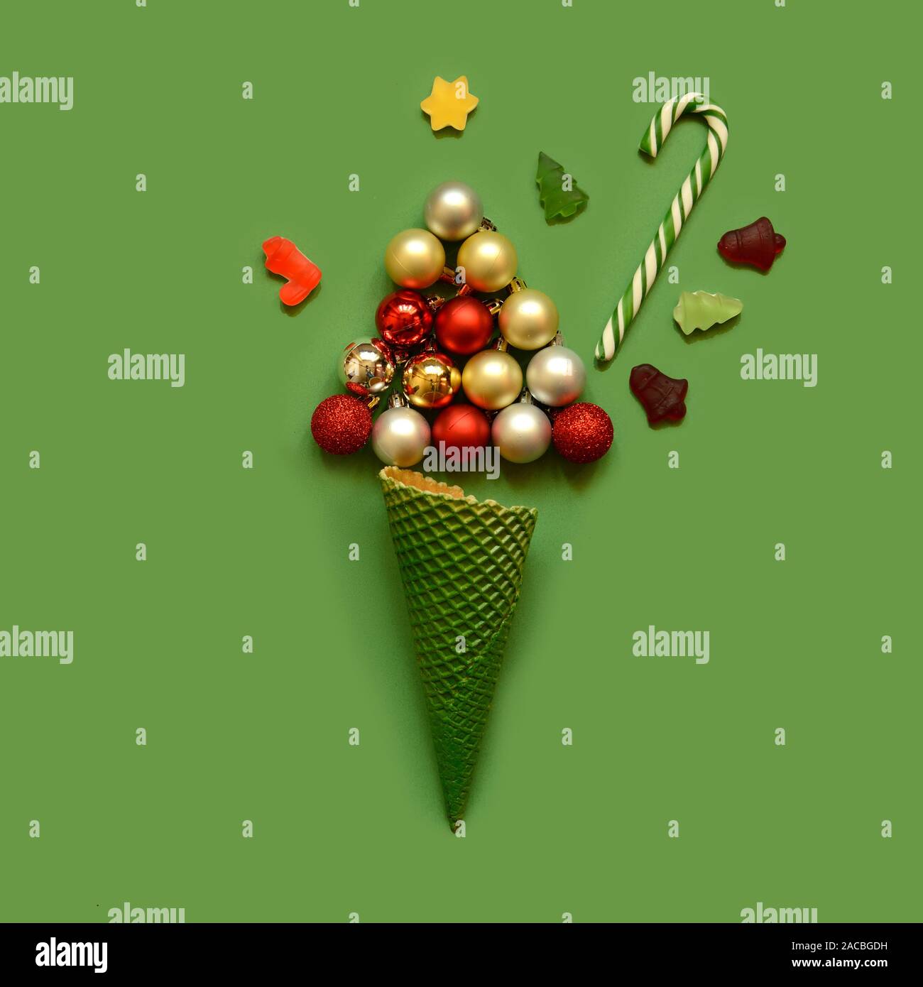Christmas composition. Ice cream cone with tree from balls,candy canes and sweets on green background. Christmas, winter, new year concept. Flat lay, Stock Photo