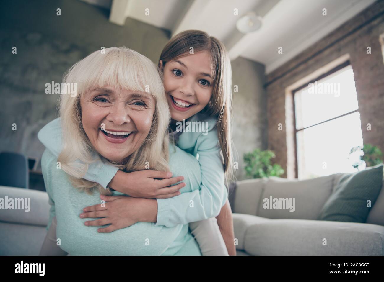 Low below angle view photo of two best friends people cute aged granny small grandchild girl hug piggyback playing funny game spend weekend together Stock Photo