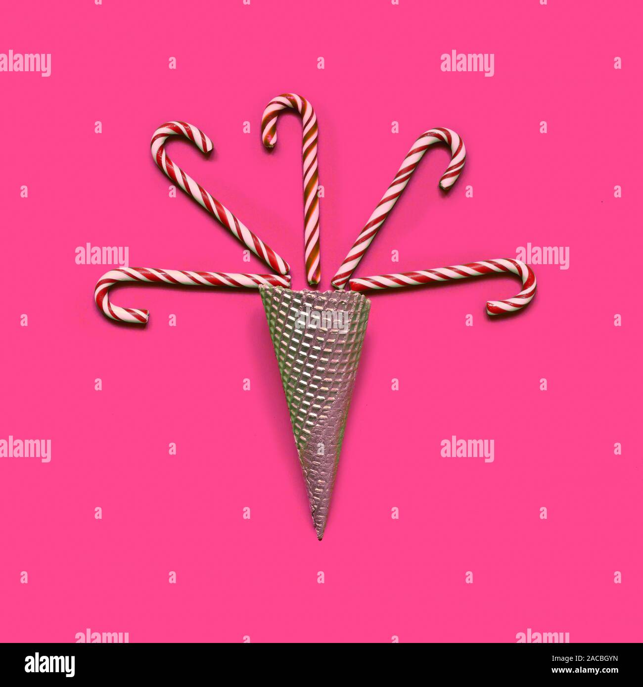 Creative minimal christmas art.Christmas candy canes in Ice Cream Cone on plastic pink background Stock Photo